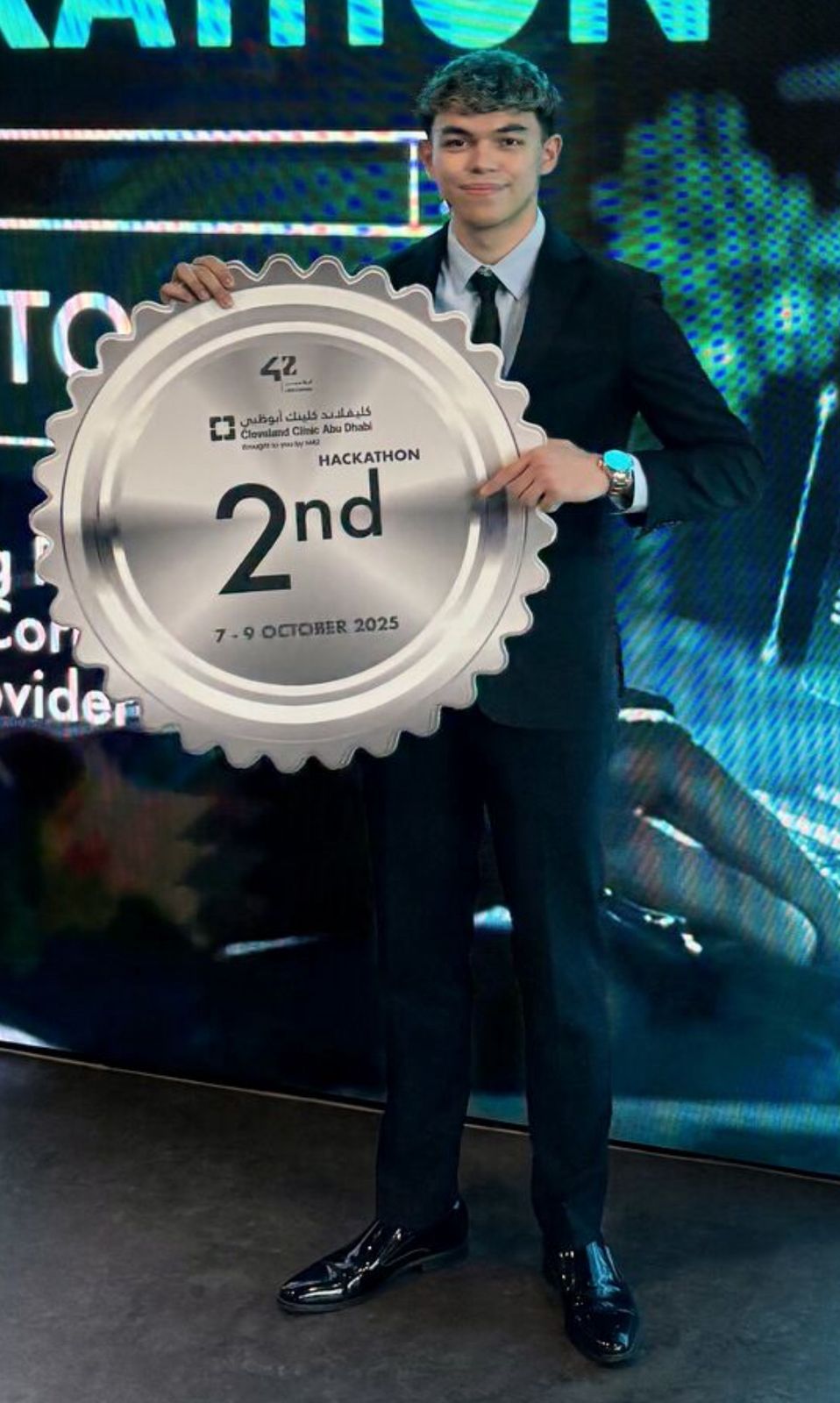 Close-up of Ismail holding the silver 2nd place hackathon plaque